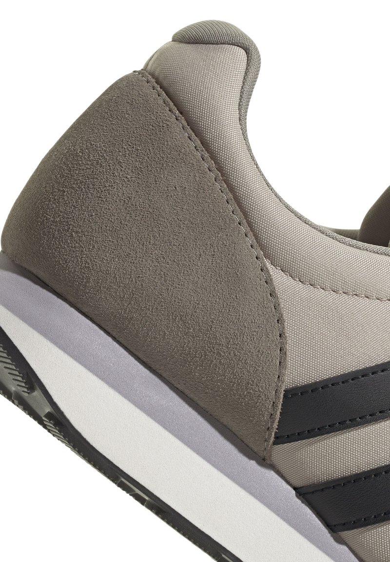 Grijze en beige sneakerhiel met zwarte strepen, textuur van suède en stoffen materialen, en een gelaagde zool in wit, grijs en zwart.