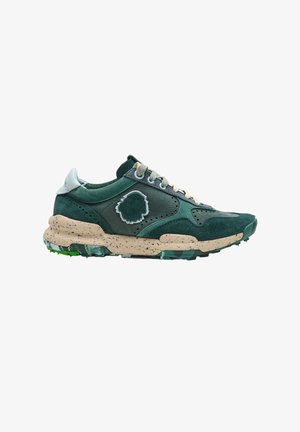 Zapatilla deportiva verde oscuro y beige con mezcla de piel y ante, suela salpicada, cordones blancos y parche decorativo irregular en el lateral.