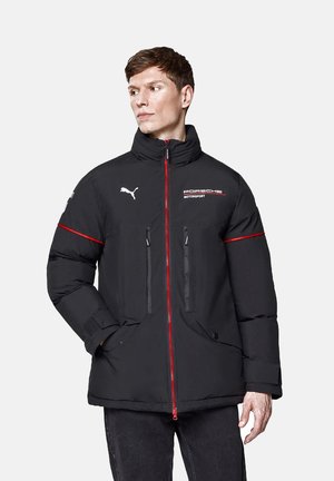Czarna pikowana kurtka z czerwonym zamkiem błyskawicznym, dwoma przednimi kieszeniami oraz haftowanym logo Porsche Motorsport. Posiada wysoki kołnierz i logo Pumy na rękawie.