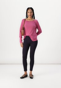 Dlhý rukáv, koralovo-ružový top s voľnejším strihom, doplnený o slim-fit námořnícku legíny. Čierne baleríny a malá hnedá taška na plece dotváraj�ú vzhľad.