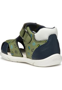 Zielono-granatowe sandały z perforowanym wzorem, regulowanymi paskami oraz nadrukowanymi motywami morskimi. Gumowa podeszwa zapewnia przyczepność.