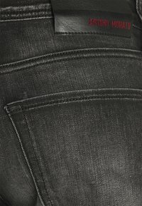 Black denim jeans featuring a textured fabric, contrasting stitching, and a leather tag with "ANTONY MORATO" in red lettering.