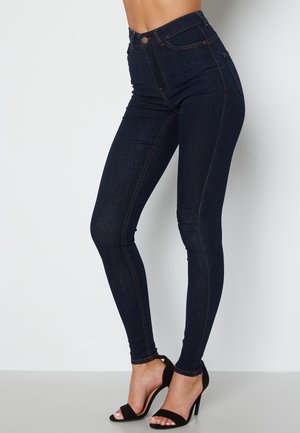 High-waisted dark denim skinny jeans with contrast stitching, featuring a front button closure and five pockets.
