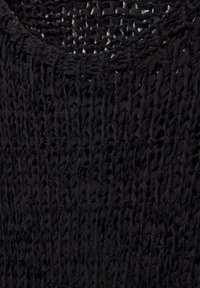 Černá pletená tkanina má otevřenou vazbu a texturovaný povrch s kulatým výstřihem, který předvádí složité vzory šití.