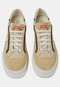 Beige sneaker with a textured canvas upper, suede accents, and contrasting olive stitching. Features white laces and a platform sole.