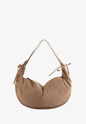 Sac à bandoulière en tissu marron présentant une forme arrondie, une bandoulière réglable avec boucle, et des liens décoratifs sur le côté. Texture douce.