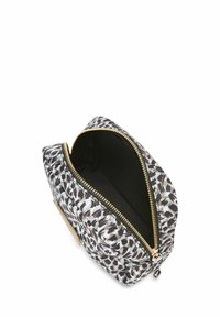 Cosmetic tas met rits, gemaakt van zwart-wit luipaardprint stof, met gouden hardware, een zachte textuur en een open bovenkant die een donkere binnenkant toont.