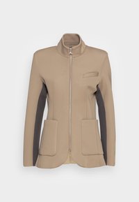 Chaqueta ajustada beige y gris oscuro con cuello alzado, cremallera frontal, un bolsillo en el pecho y dos grandes bolsillos frontales de parche.