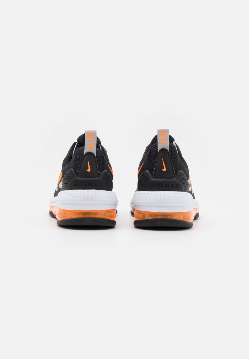 Para czarnych i pomarańczowych sneakersów Nike Air Max widocznych z tyłu, z białymi podeszwami i pętlami do ciągnięcia z napisem "AIR".