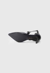 Black high-heeled shoe with a pointed toe and an ankle strap. Features a textured sole and a smooth leather upper.