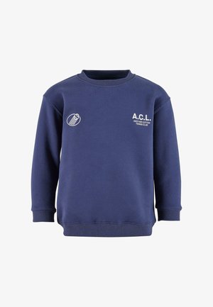 Tumedat sinine puuvillane dressipluus ribatud ümarate kraega. Omab valgeid trükitud graafikaid: "A.C.L." ja tenniseklubi logot vasakul rinnal.