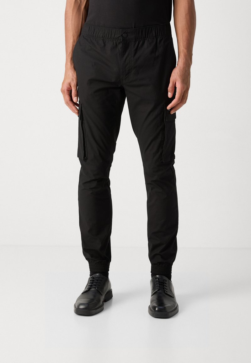 Pantaloni cargo neri realizzati in tessuto leggero, con vita elasticizzata, tasche con zip e polsini caviglia affusolati.