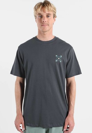 T-shirt en coton gris avec col rond, manches courtes et petit motif de feuille turquoise sur le côté gauche de la poitrine. Coupe classique.