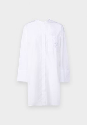 Camicia bianca con colletto, maniche lunghe, taschino frontale con un delicato ricamo blu e un design pulito e minimale.