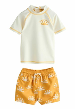 Camiseta de protección solar de manga corta en color crema claro con el texto "SUNNY DAYS", combinada con pantalones cortos amarillos con patrones de sol blancos y una cintura elástica.