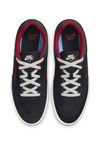 Čierne semišové skate tenisky s červeným vnútorným poťahom, sivými šnúrkami a bielou gumovou podrážkou. Na jazyku sa nachádza branding Nike SB.