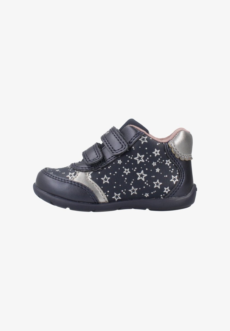 Zapato infantil de color azul marino oscuro con un patrón de estrellas plateadas, dos correas de velcro y detalles plateados en el talón. Fabricado con material sintético. Diseño de perfil bajo.