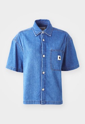 Short-sleeve denim shirt in light blue, featuring a button-up design, chest pocket, and prominent logo patch. Smooth texture and casual fit.