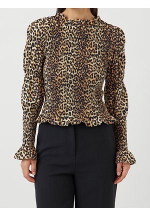 Mujer con blusa de manga larga con estampado de leopardo, fruncida con volantes en los puños y el dobladillo, combinada con pantalones negros sobre un fondo liso.