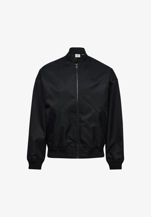 Sort bomberjakke med lynlås, ribstrikket krave, manchetter og kant, med to sidelommer og diskret logo på brystet.