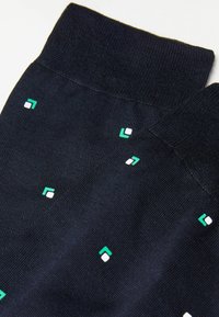 Calcetines azul marino con textura suave y patrones geométricos en verde y blanco. El puño es acanalado, lo que proporciona un ajuste seguro.