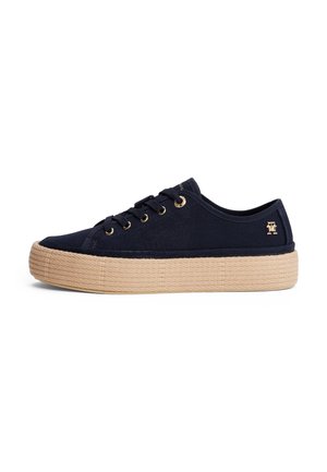Zapatilla deportiva de corte bajo en azul marino con suela plataforma texturizada beige y ojales dorados, con un pequeño logo dorado en el lateral cerca del talón.