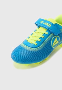 Μπλε και κίτρινο ποδοσφαιρικό παπούτσι με υφασμένο συνθετικό επάνω μέρος, κλείσιμο με κορδόνια και βέλκρο, με χυτό λαστιχένιο πέλμα και τάπες.