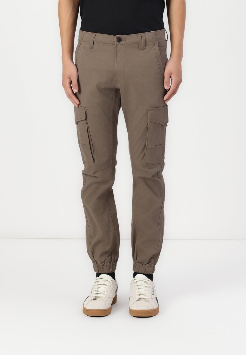 Pantalones cargo en marrón claro, con puños elásticos, bolsillos laterales y un corte regular. Fabricados con una tela resistente de textura suave.