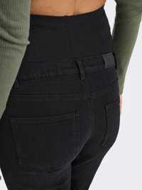 Blugii negri din denim cu talie înaltă au o talie elastică, două buzunare în spate și un finisaj neted. Țesătura are o ușoară elasticitate pentru confort.