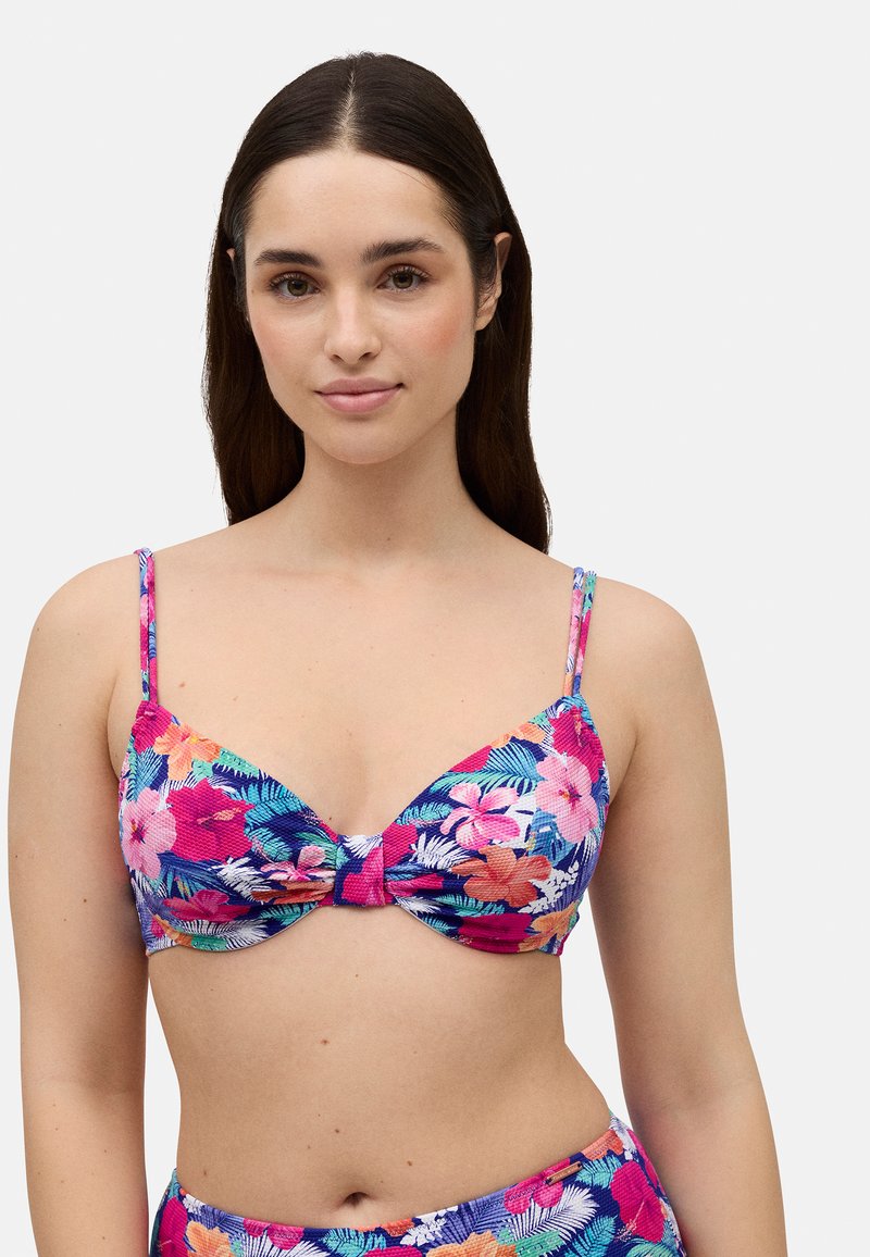 Top de bikini floral con diseño de frente retorcido, tirantes ajustables y vibrantes patrones tropicales en rosa y azul sobre una tela texturizada.