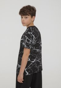 T-shirt nero a maniche corte con motivo in marmo bianco, realizzata in morbido cotone, con scollatura rotonda e vestibilità comoda.