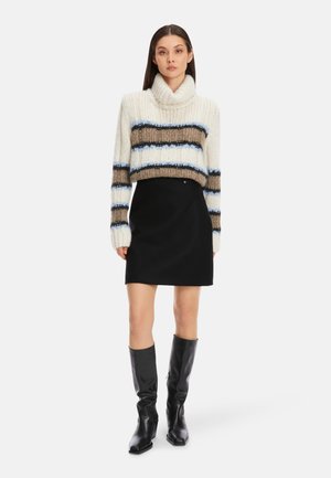 Chunky knit sweater in cream with horizontal stripes in brown and blue, paired with a black mini skirt and knee-high black heeled boots.