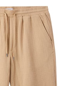 Pantaloni in tessuto beige texturizzato con vita elasticizzata, coulisse e tasche laterali, caratterizzati da un motivo stropicciato per un tocco di dettaglio in più.