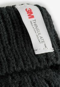 Schwarzer gestrickter Stoff mit strukturierter Oberfläche, versehen mit einem weißen Etikett, auf dem "3M THINSULATE" in rot und schwarz steht, was auf das Isoliermaterial hinweist.