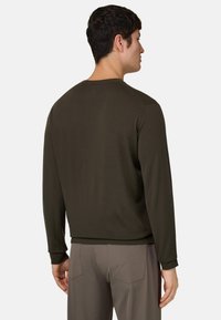 Camisa de manga larga de color verde oliva oscuro con cuello redondo, puños acanalados y textura suave. Diseño sin estampados y corte sencillo.