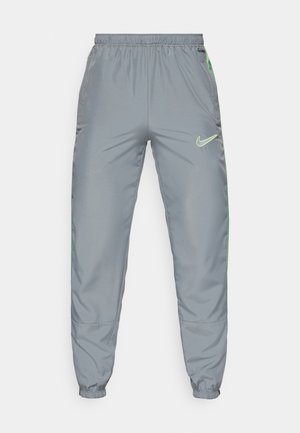 Pantalones de chándal Nike en poliéster gris con cintura elástica, puños cónicos y acentos laterales en verde neón; cuenta con el logo en la parte frontal derecha.