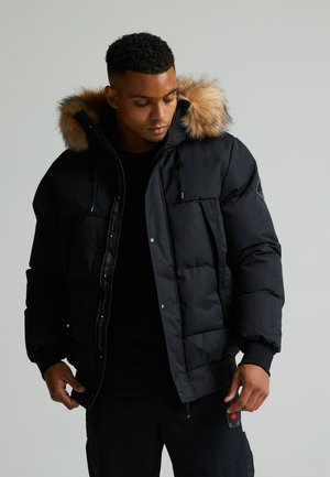 Black puffer jacket with a fur-trimmed hood, featuring a zippered front, snap buttons, and a large pocket on the chest.
