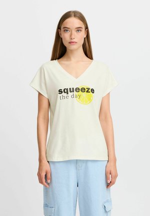 T-shirt en coton jaune clair avec un col en V, des manches courtes et un imprimé graphique représentant le texte "squeeze the day" et une tranche de citron.