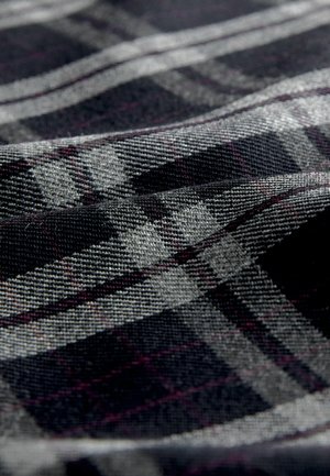 Schwarz-graues Karofabric mit Hints von Lila, das eine strukturierte Webart und ein geometrisches Muster aufweist, welches visuelle Tiefe erzeugt.