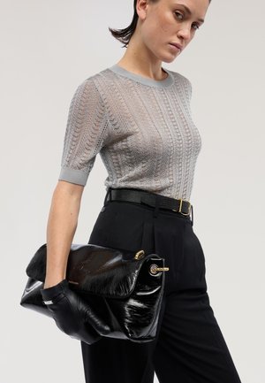 Sort skindclutch med fold-over klap, guldfarvet hardware og en tekstureret finish. Kombineret med en grå strikbluse og sorte bukser.