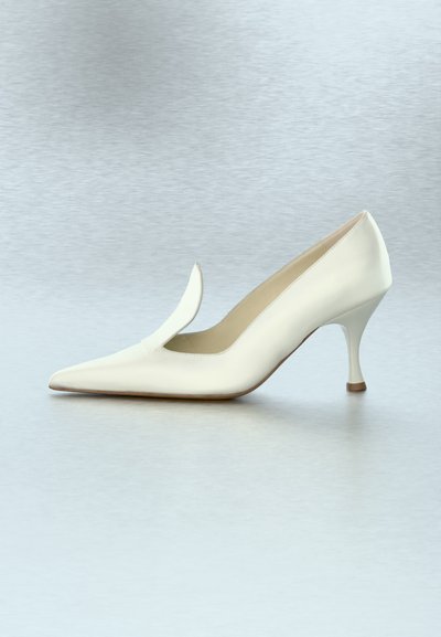 Λευκό δερμάτινο γυναικείο παπούτσι μυτερό με ψηλό τακούνι, καμπυλωτό τακούνι και διπλωμένη λεπτομέρεια στη πάνω πλευρά, με φόντο απλό ανοιχτόχρωμο.