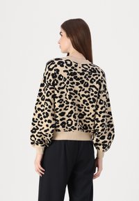 Pulover s leopard uzorkom u bež i crnoj boji, s okruglim izrezom, opuštenim krojem i naboranim rukavima. Mekana pletena tekstura.