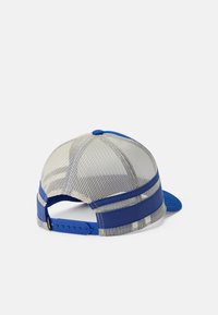 Mėlyna ir smėlio spalvos tinklelio krovinio kepurė su reguliuojamu snapback uždarymu ir kietais mėlynais priekiniais skydeliais, rodoma iš nugaros ant balto fono.