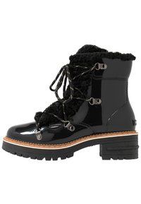 Stivaletto nero in vernice con colletto in pelliccia sintetica, hardware argentato, suola intermedia a contrasto e suola in gomma texturizzata. Presenta design con lacci.