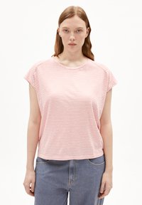 T-shirt à manches courtes rayé rose et blanc avec un col rond et une coupe décontractée, associé à un jean bleu taille haute. Texture de tissu douce.