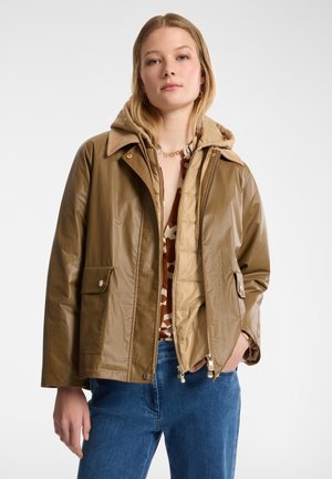Giacca impermeabile marrone con cappuccio, chiusura con zip, due tasche frontali e un rivestimento interno trapuntato. Presenta una texture liscia e lucida.