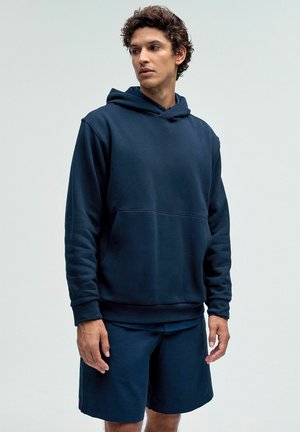Marineblå hoodie med forlommer, lavet af blødt stof; parret med matchende shorts. Casual pasform, minimalistisk design, ingen synlig branding.