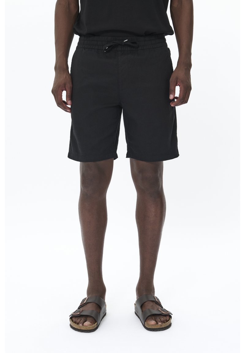 Black shorts made from lightweight fabric, featuring an elastic waistband with drawstring and side pockets. Worn with brown sandals.