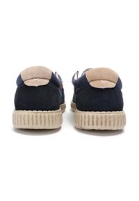 Chaussures en daim bleu marine foncé avec des accents de talon en daim beige et une semelle en caoutchouc texturé marron clair. Présente un design basse et des coutures minimales.