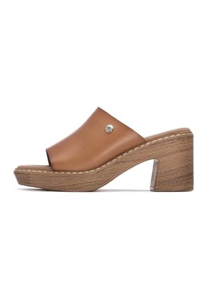 Sandalia tipo cuña de piel marrón, con punta abierta y tacón inclinado, que presenta un tachuela plateada decorativa y un acabado texturizado similar a la madera.